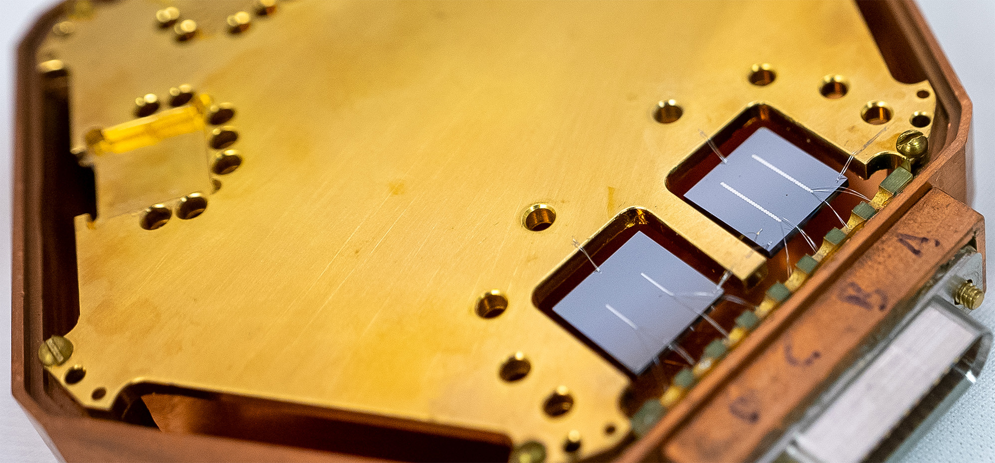Close-up of a hexagonal structure holding two square chips, each with two reflective lines.
