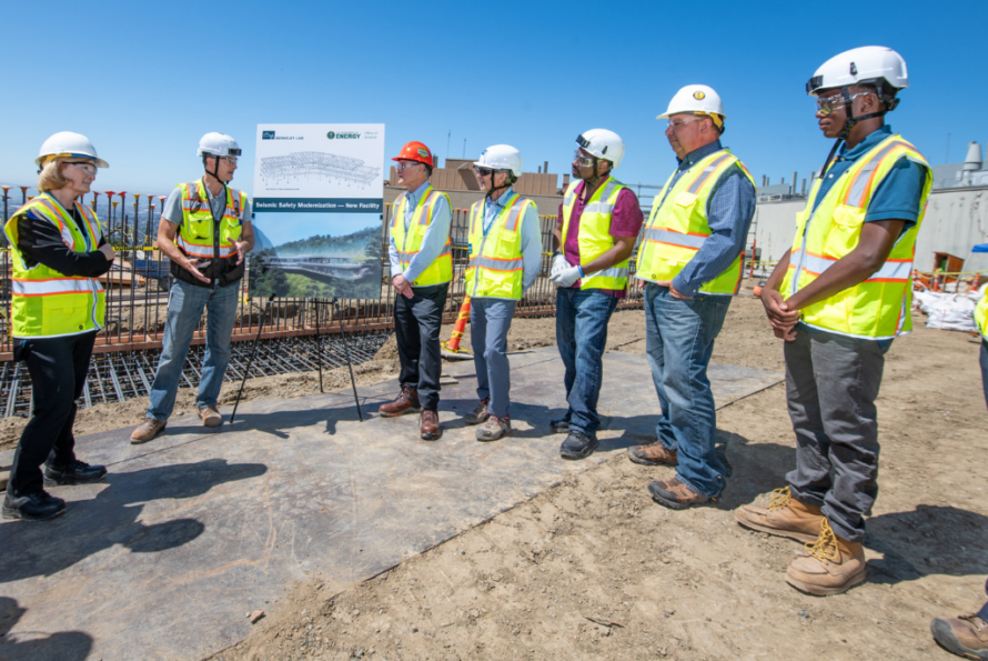 Seven people in yellow vests and hard hats