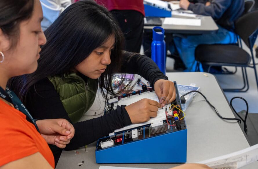 Two people over an electronic board