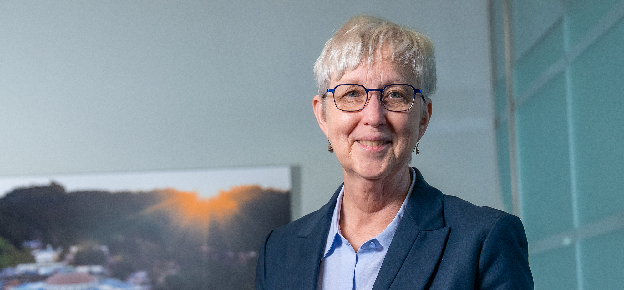Katherine Yelick standing in front of an aerial image of Berkeley Lab.
