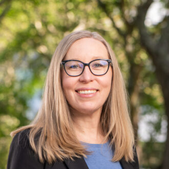 Person with glasses wearing a light blue shirt and black sweater