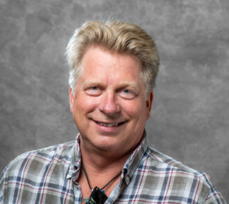 Person wearing flannel shirt and rope necklace