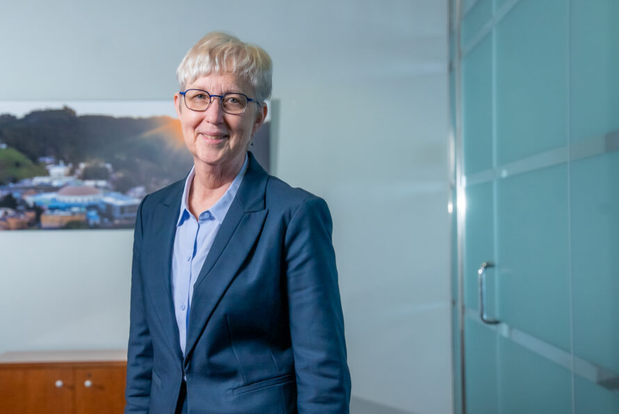 Katherine Yelick standing in front of an aerial image of Berkeley Lab.